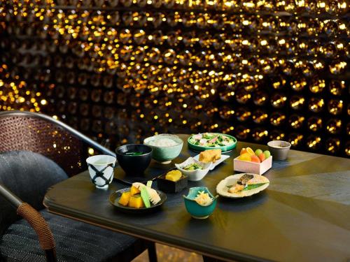 a table with bowls of food on top of it at Hotel Sosei Sapporo MGallery Collection in Sapporo
