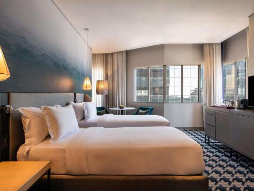 a hotel room with two beds and a table at Pullman Cape Town City Centre in Cape Town
