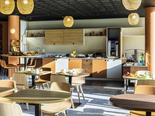 Mercure Agen Centre في آجا: مطعم مع طاولات وكراسي ومطبخ
