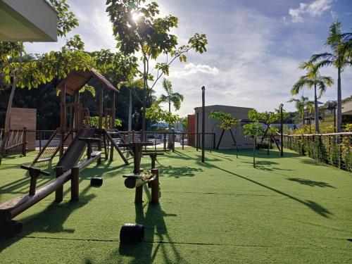 einen Park mit einem Spielplatz mit grünem Gras in der Unterkunft Apartamento com jardim em condomínio resort in Parnamirim