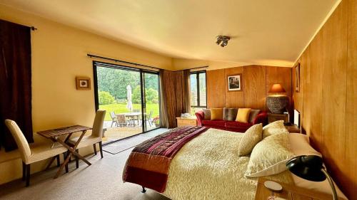 Hawkshead Boutique Studio & Gardens في ماكارورا: غرفة نوم بسرير كبير ونافذة كبيرة
