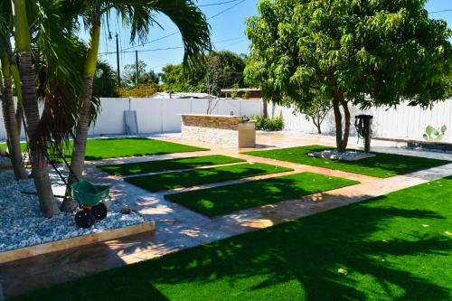 a garden with palm trees and a fence at Family-Ready 3 BDR Oasis Near Pompano Beach in Pompano Beach