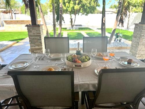 a table with a bowl of fruit and wine glasses at Family-Ready 3 BDR Oasis Near Pompano Beach in Pompano Beach