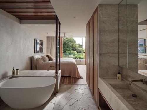 un bagno con vasca e una camera da letto con un letto di Este Estate a Byron Bay