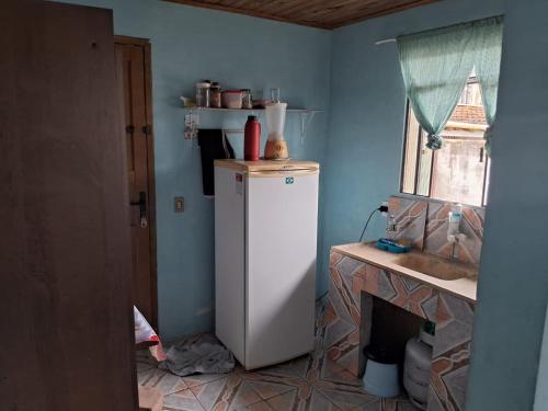 a kitchen with a white refrigerator and a fireplace at Pousada da Lu in São Francisco do Sul
