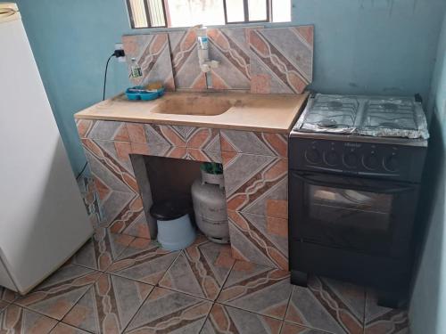 a small kitchen with a stove and a sink at Pousada da Lu in São Francisco do Sul