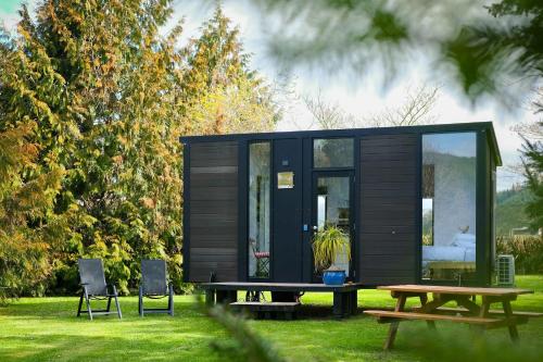 a black tiny house with a picnic table and chairs at Ryan's Ranch by Tiny Away in Belgrove