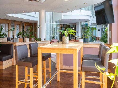 a restaurant with a wooden table and chairs at Atomis Hotel Munich Airport by Mercure in Oberding