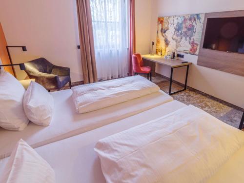 2 bedden in een kamer met een bureau en een stoel bij Atomis Hotel Munich Airport by Mercure in Oberding