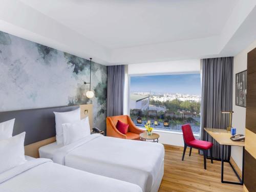 a hotel room with two beds and a window at Novotel Jaipur Convention Centre in Jaipur