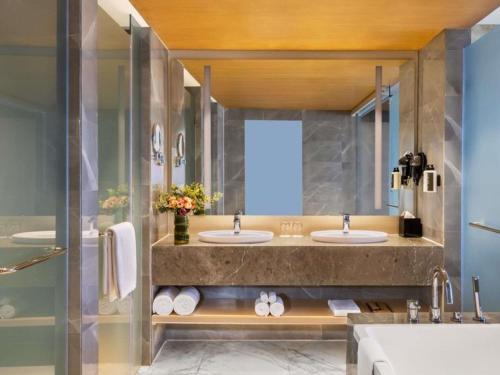 a bathroom with three sinks and a large mirror at Novotel Jaipur Convention Centre in Jaipur