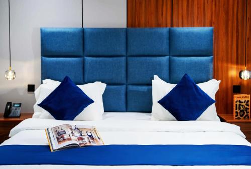 uma cama com cabeceira azul acolchoada e travesseiros azuis em Diamond Jardin em Riade