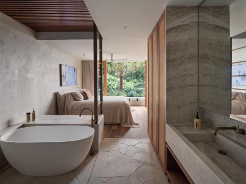 un bagno con vasca e una camera da letto con un letto di Este South a Byron Bay