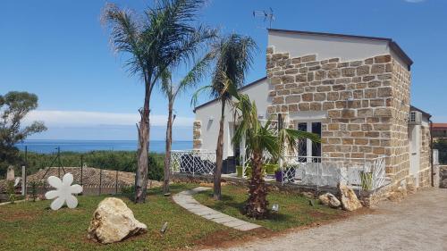 a stone house with palm trees and the ocean at Maresol in Trappeto