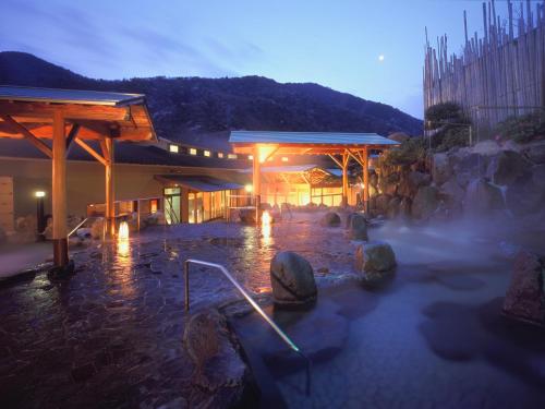 a building with a hot spring with rocks in the water at Hakonenomori Okada in Hakone