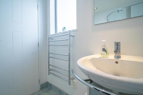 een witte badkamer met een wastafel en een spiegel bij Seaview Home in Khandallah in Wellington
