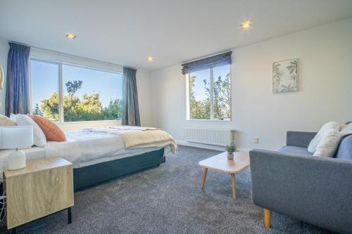 een slaapkamer met een bed, een bank en ramen bij Seaview Home in Khandallah in Wellington