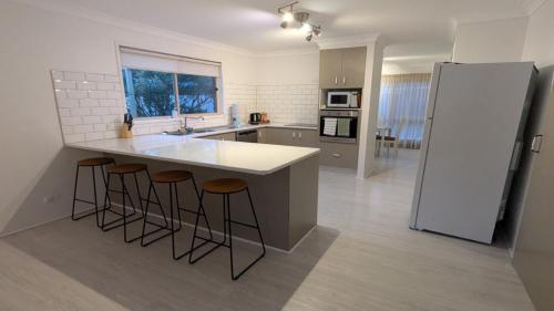 cocina con encimera blanca grande y taburetes en Flamingo Sunset Retreat, en Old Bribie