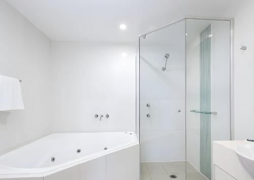 een witte badkamer met douche en wastafel bij One-Bedroom Lagoon Spa Apartment in Salamander Bay