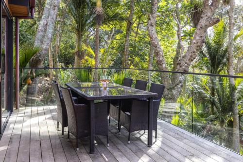 a black table and chairs on a deck with trees at Te Toki Treehouse and Studio in Waiheke Island