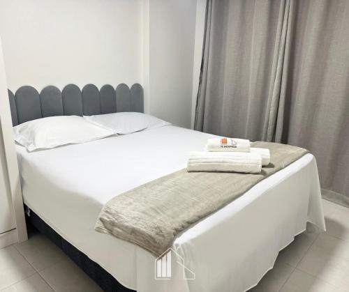 a white bed with two towels on top of it at Apartamento na Praia dos Milionários - 100M do Mar in Cururupe