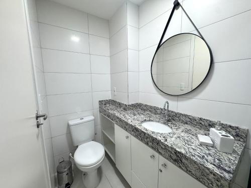 a white bathroom with a toilet and a mirror at Apartamento na Praia dos Milionários - 100M do Mar in Cururupe