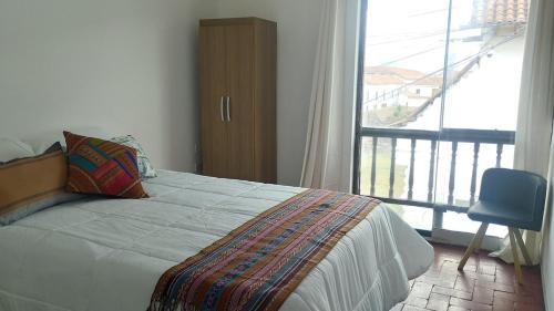 a bedroom with a bed and a window and a chair at The heart of Tawa Wawa Wasi in Cusco