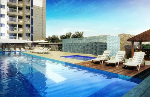 a swimming pool with chairs and a building at Alto padrão com ar, garagem, sacada integrada in Belém