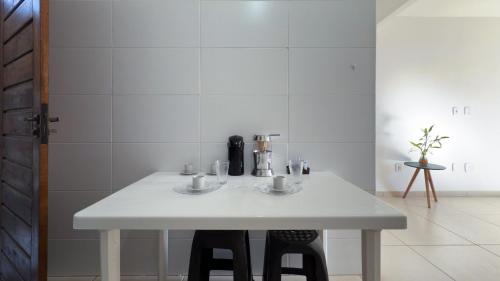 a white table in a room with two stools at Duplex em Itaúna 4min da Praia que ocorre o WSL, 1min da pista de skate do LS, pracinha com parque infantil, quadra de futebol, tudo isso a 1 min da duplex, perto do comércio, wi-fi super rápido, estacionamento gratuito, monitoramento 24hrs in Saquarema