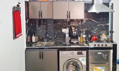 een keuken met een fornuis en een wasmachine bij Apartment Comfortable furnished studio in Sale