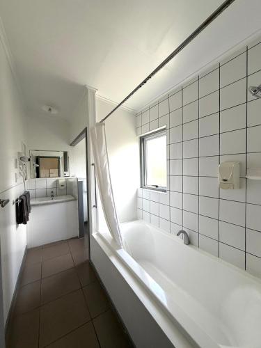 a white bathroom with a tub and a window at Central Court Motel in Whangarei