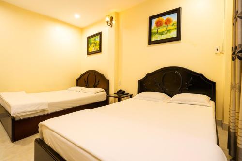 two beds in a hotel room with white sheets at Cát Tường Hotel in Ho Chi Minh City