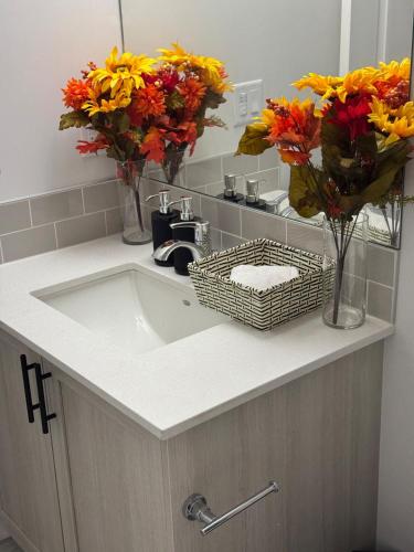 a bathroom sink with flowers in vases on it at Luxury Haven by Kc & Flo in YYC