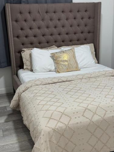 a large bed with a padded headboard and pillows at Luxury Haven by Kc & Flo in YYC