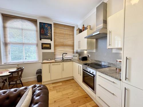 Una cocina con gabinetes blancos y una mesa y un sofá. en Flat 1, Waterloo Apartments, en Radstock