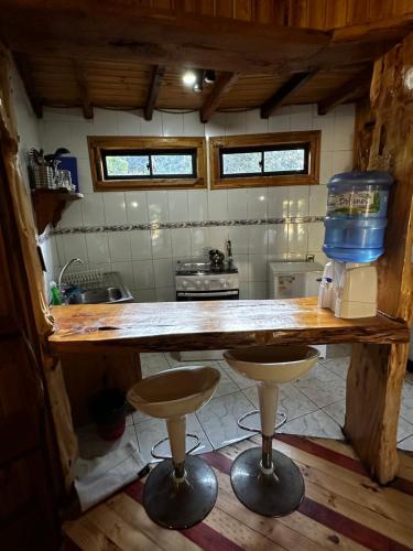 a kitchen with a wooden table and two stools at Reserva los Bollenes in Constitución