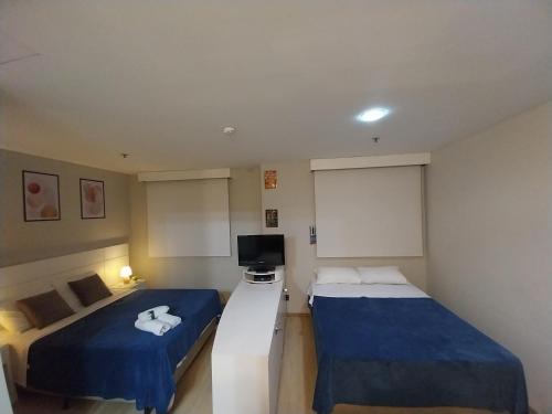 a hotel room with two beds and a television at Flat Wyndham2 Paulista com estacionamento in Sao Paulo