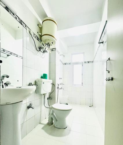 a white bathroom with a toilet and a sink at Hotel Swagat in Pelling