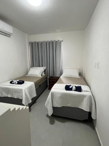 a bedroom with two beds with white sheets at Condominium Village V Praia dos Carneiros-PE in Tamandaré