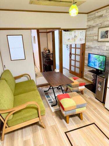 a living room with a green couch and a table at Ume-no-Yado Villa 梅の宿 - A house with a traditional Japanese garden in Osaka