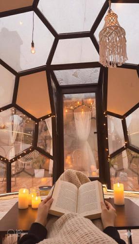 a person reading a book while sitting at a table with candles at Elegant Retreat- Sleep 10-Boho Dome Lounge-Hot Tub-Games-Golf-Serene Getaway in Sacramento