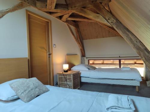 una camera con due letti in una stanza con soffitti in legno di Gîte rustique au calme avec cheminée et jardin, 4 pers. - FR-1-489-600 a La Faye