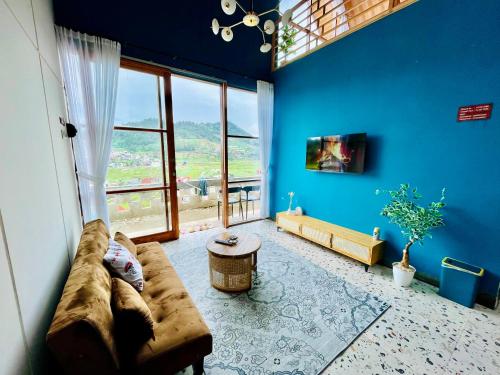 - un salon avec un grand canapé et un mur bleu dans l'établissement Arutala Villa tiitk 0 Dieng View Pegunungan, à Diyeng