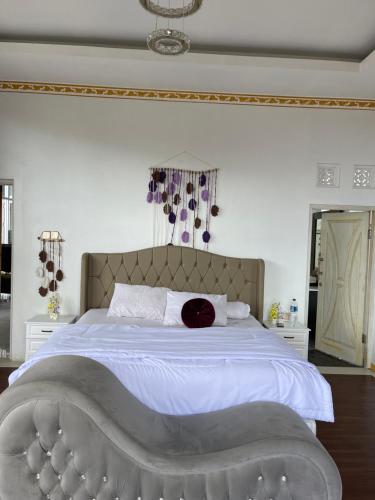 Un dormitorio con una cama grande con sábanas blancas y una almohada roja. en As Family Villa, en Singaraja