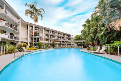 a large swimming pool in front of a building with palm trees at Coral Coast Resort Accor Vacation Club Apartments in Palm Cove