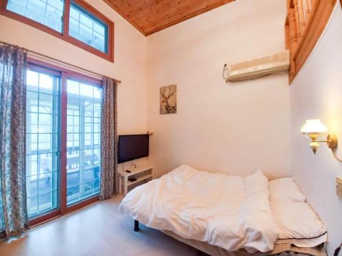a bedroom with a bed and a tv and windows at Hongcheon Riverhill Stay in Torung-gol