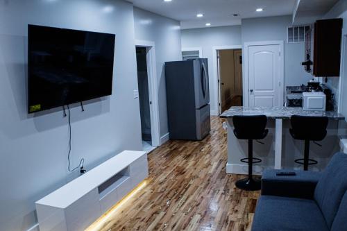a living room with a tv on the wall and a kitchen at Modern 3BR Walk to Subway 2 Min to LOGAN Airport in Boston