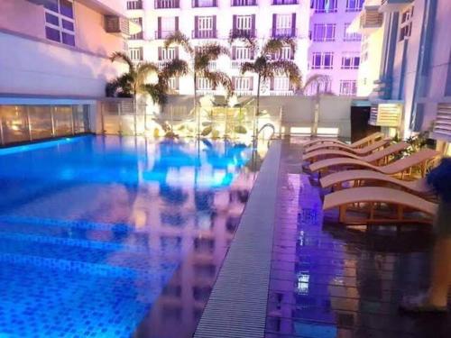 a large swimming pool with chairs and a building at A&G Condotel at 101 Newport Near NAIA T3 in Manila