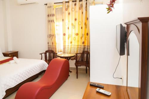 a room with a bed and a chair and a tv at Mây Trắng Hotel in Ho Chi Minh City