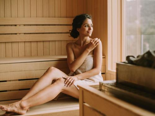 a woman sitting in a sauna at Mercure Aix-les-Bains Domaine de Marlioz Hôtel & Spa in Aix-les-Bains